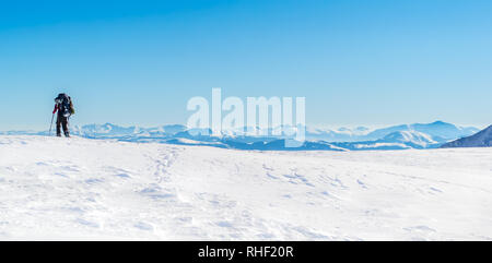 Passeggiate turistiche sulla neve e lasciando tracce. Sullo sfondo di una catena montuosa. Cielo sereno e soleggiato. L'inverno. L'Ucraina Foto Stock