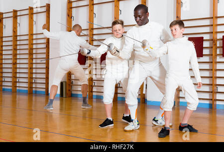 Focalizzato diligente grave ragazzi schermitori attento ascolto professional Efficient friendly scherma pulmann in palestra Foto Stock