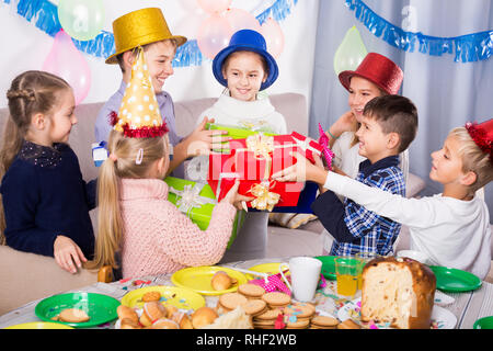 Soddisfatti i bambini presentando doni alla bambina durante la festa di compleanno Foto Stock