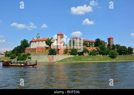 Cracovia in Polonia - 10 luglio 2018. Una barca turistica va passato il Castello di Wawel sul fiume Vistola. Il campanile della cattedrale di Wawel può anche essere visto Foto Stock