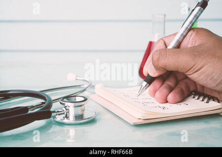 La mano del medico o scienziato iscritto con lo stetoscopio e il tubo di prova Foto Stock