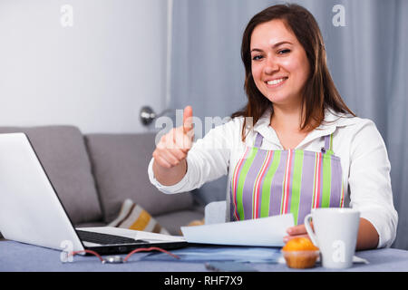 Giovane donna navigando attraverso utili suggerimenti per la cottura in Internet Foto Stock