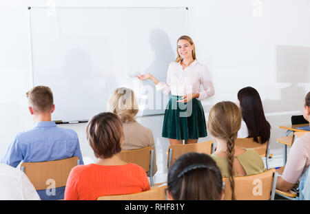 Gentile giovane insegnante femminile lezioni di adulto attento agli studenti presso auditorium Foto Stock