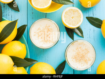 Vaso di vetro con Cheesecake al limone con limoni freschi bluw su sfondo di legno Foto Stock