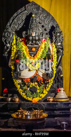Belavadi, Karnataka, India - 2 Novembre 2013: Veera Narayana Tempio. Primo piano della Yoganarasimha idolo statua nero decorato con fiori colorati leis. Foto Stock