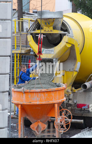 Neuwied, Germania - 1 Febbraio 2019: un trucker riempie la malta al di fuori del suo mortaio carrello in un silo di cemento Foto Stock