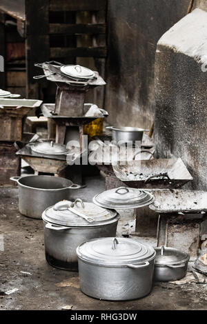 Gruppo di carbone di legna rustico stufe e pentole, padelle e casseruole sul pavimento al mercato locale di Toliara, Madagascar. Foto Stock