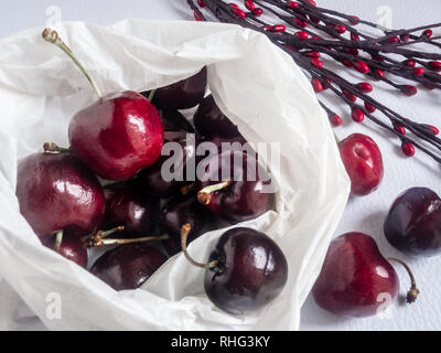 Borsa bianca di ciliege rosse su sfondo bianco Foto Stock