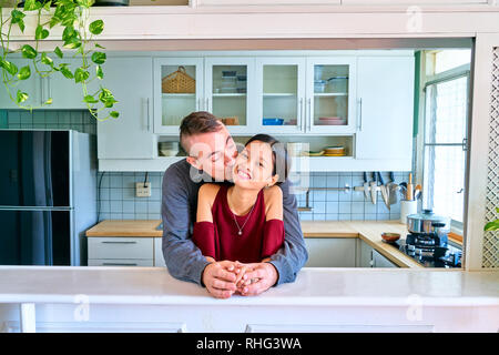 Coppia adorabile che pongono - tenendo le mani e baciando la guancia Foto Stock