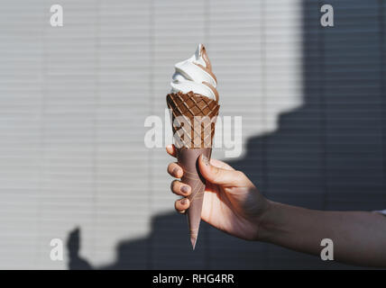 Donna mano azienda gelato cono di cialda in estate Foto Stock