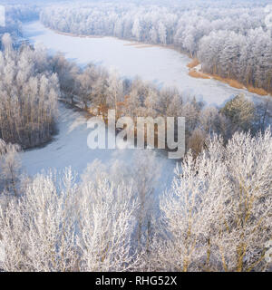 Rime e brina alberi di copertura. Vista aerea della neve-coperta di foresta e il lago dall'alto. Paesaggio invernale. Paesaggio foto catturate con drone. Foto Stock