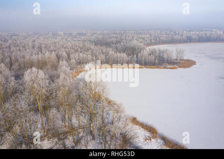 Rime e brina alberi di copertura. Vista aerea della neve-coperta di foresta e il lago dall'alto. Paesaggio invernale. Paesaggio foto catturate con drone. Foto Stock