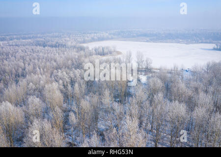 Rime e brina alberi di copertura. Vista aerea della neve-coperta di foresta e il lago dall'alto. Paesaggio invernale. Paesaggio foto catturate con drone. Foto Stock