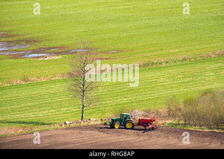 Trattore con una seminatrice su un campo in primavera Foto Stock