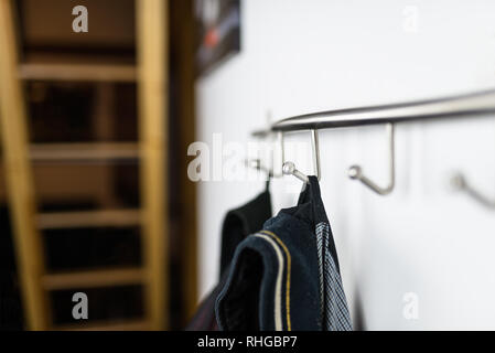 Dark mens giacche appeso ad un gancio in hause, su una staffa a parete. Foto Stock