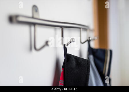 Dark mens giacche appeso ad un gancio in hause, su una staffa a parete. Foto Stock