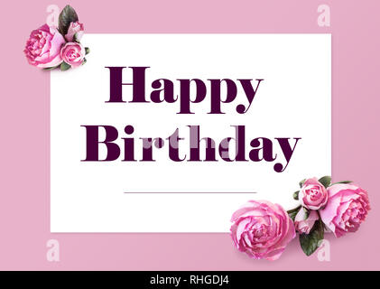 Elegante Happy Birthday Greeting Card. Testo sul foglio di carta bianco e fiori isolati di peonie su uno sfondo di colore rosa. Layout creativi per una vacanza Foto Stock