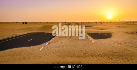 La sabbia è tenuto su una strada nel deserto vicino a Dubai negli Emirati Arabi Uniti. Foto Stock