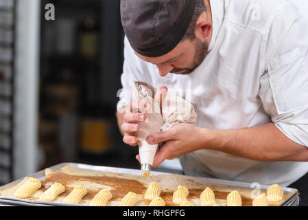 Pastry Chef con il sacchetto per la pasticceria la spremitura di crema alla pasticceria . Foto Stock