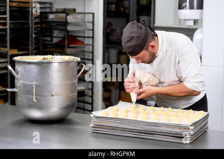 Pastry Chef con il sacchetto per la pasticceria la spremitura di crema alla pasticceria . Foto Stock