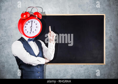 Un uomo con un orologio al posto di una testa sullo sfondo di una lavagna per Chalk Foto Stock