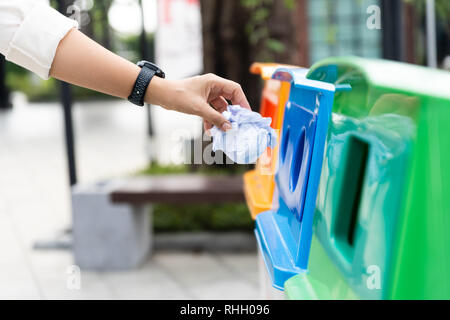 Ritratto closeup donna canto di gettare la carta stropicciata nel contenitore di riciclaggio. Foto Stock