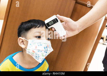 Controllo misurare i livelli di febbre bambini utilizzando da digitale Termometro a infrarossi. Foto Stock