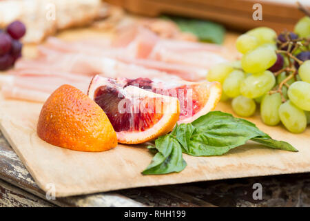 Arancio sanguigno con fette di salumi in legno bordo esterno per intrattenere un picnic. Foto Stock