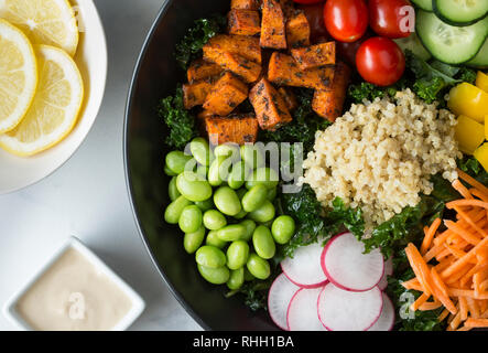 Vista aerea di sana insalata di cavolo ciotola con verdure - patate dolci, pomodori, cetrioli, peperoni, carota, ravanello e edamame con la quinoa. Foto Stock