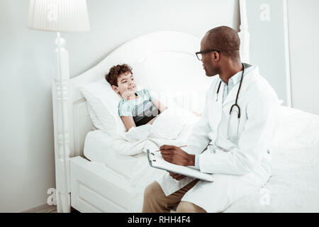 Rilassante dai capelli ricci kid comunicante con il medico Foto Stock