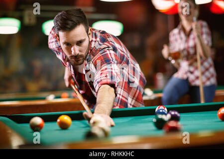 Giovane uomo serio giocando a biliardo nel club Foto Stock