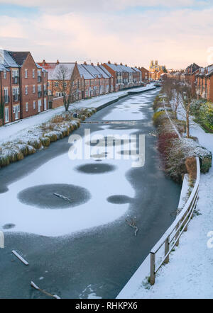 Il congelamento canal ricoperta di neve fiancheggiate da case di città e le antiche minster all'orizzonte su un luminoso inverno mattina, Beverley, Yorkshire, Regno Unito. Foto Stock