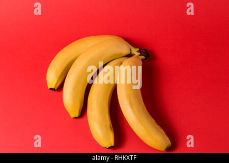 Il minimalismo creativi concetto. Concetto di imprevisti. Appartamento vista laici di banana frutto pattern luminoso su sfondo rosso. Foto Stock