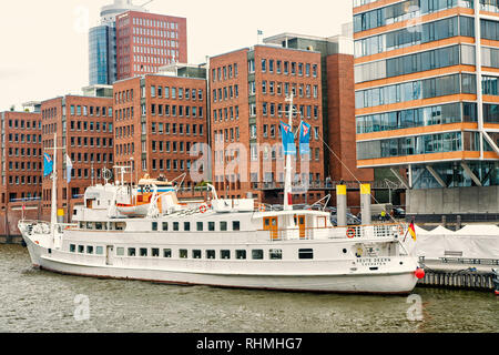 Amburgo, Germania - 07 Settembre 2017: acqua, viaggio, viaggiare, viaggio. Nave al molo del traghetto sul paesaggio urbano in background. Trasporto fluviale trasporto vacanza scoperta wanderlust Foto Stock