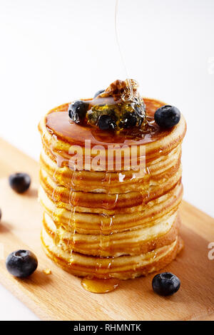 American dolce casalingo pila di pancake o le frittelle con mirtillo Frutta, noci e miele, deliziosi dessert per colazione, su sfondo bianco. Sel Foto Stock