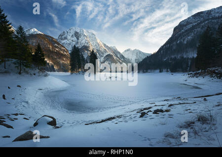 Congelati e coperta di neve in inverno Lago del Predil splendido lago alpino nel nord Italia vicino alla frontiera slovena. Alpi Giulie Italia Foto Stock