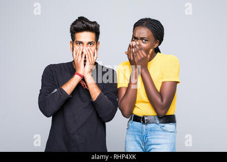 Ritratto di una giovane coppia multirazziale indian l uomo e la donna africana scioccato emozione su sfondo grigio Foto Stock