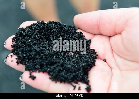 Sabbia nera sulla mano dalla grande isola di Hawaii Foto Stock