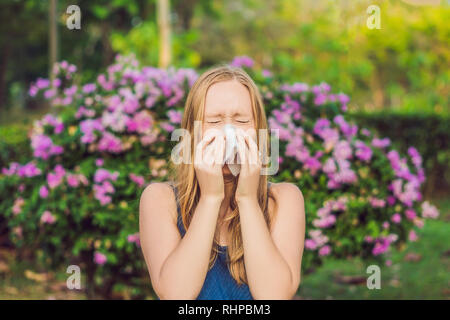 Allergia da polline concetto. Giovane donna sta per starnutire. Alberi fioriti in background Foto Stock