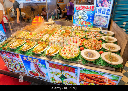 XIAMEN, Cina - 09 ottobre: Street stallo di cibo che serve piatti di pesce in un mercato notturno locale su ottobre 09, 2018 a Xiamen Foto Stock