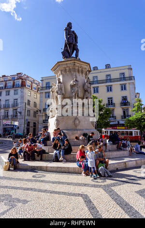 Turisti che si siedono attorno al Luís de Camões statua a Praça Luís de Camões di Lisbona, Portogallo Foto Stock