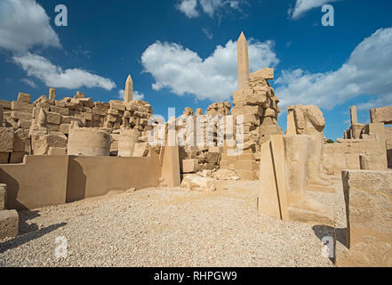 Outodoor cortile e il grande muro di pietra al tempio di Karnak cortile in Luxor Egitto con obelisco e cielo blu sullo sfondo Foto Stock