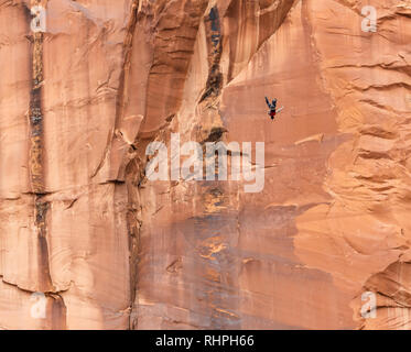 Aaron Stuyvenberg salta da un punto di uscita chiamato lapide nei pressi di Moab Utah Foto Stock
