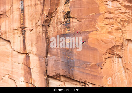 Aaron Stuyvenberg salta da un punto di uscita chiamato lapide nei pressi di Moab Utah Foto Stock
