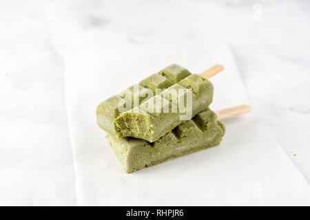 Due verde sorbetto vegano popsicles su sfondo bianco Foto Stock
