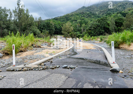 Una strada che conduce ad un ponte sopra il Fiume Barron viene allagata e danneggiato durante un pesante monsone, Cairns, estremo Nord Queensland, FNQ, QLD, Australia Foto Stock