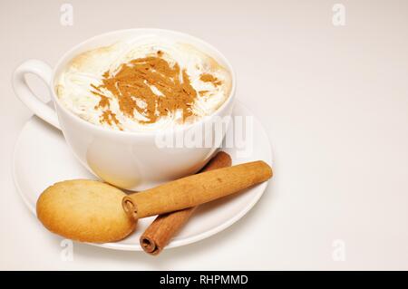 In prossimità di una calda tazza di cappuccino con biscotti e la stecca di cannella come decorazione. Vista laterale superiore, spazio di copia Foto Stock