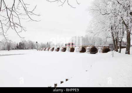 Karlstad, Svezia - 31 Gennaio 2019: uno rosso il trasporto pubblico buss sul vecchio arco in pietra ponte che attraversa il fiume Klaralven. Foto Stock