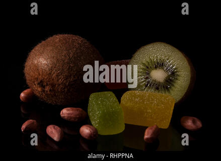 Kiwi, marmellate di frutta a guscio e di arachidi con la riflessione su una lucida sfondo nero. Foto Stock