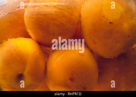 Conserve di albicocche e pesche in un vaso di vetro con sciroppo dolce. Cucinato a casa e appena arrivato dal seminterrato per lo stoccaggio dei prodotti inscatolati. Foto Stock